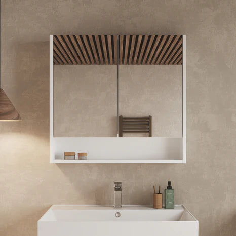 Gloss white double-door mirror cabinet mounted above a sink in a styled bathroom setting